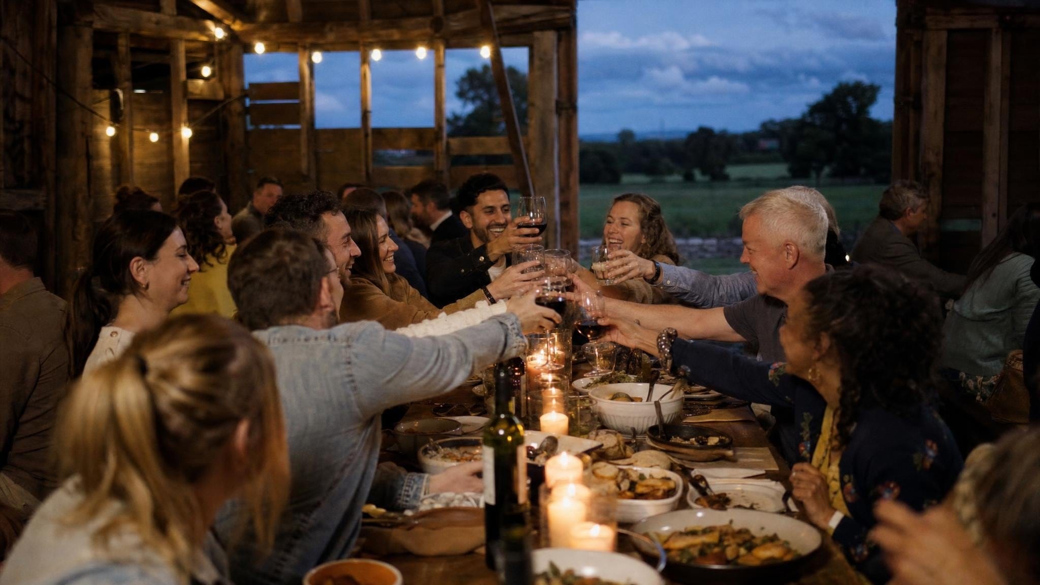 A team offsite dinner at a long table in a countryside barn