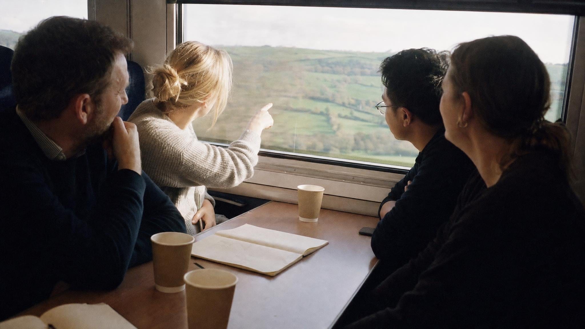 Four colleagues travelling together on a train through the countryside